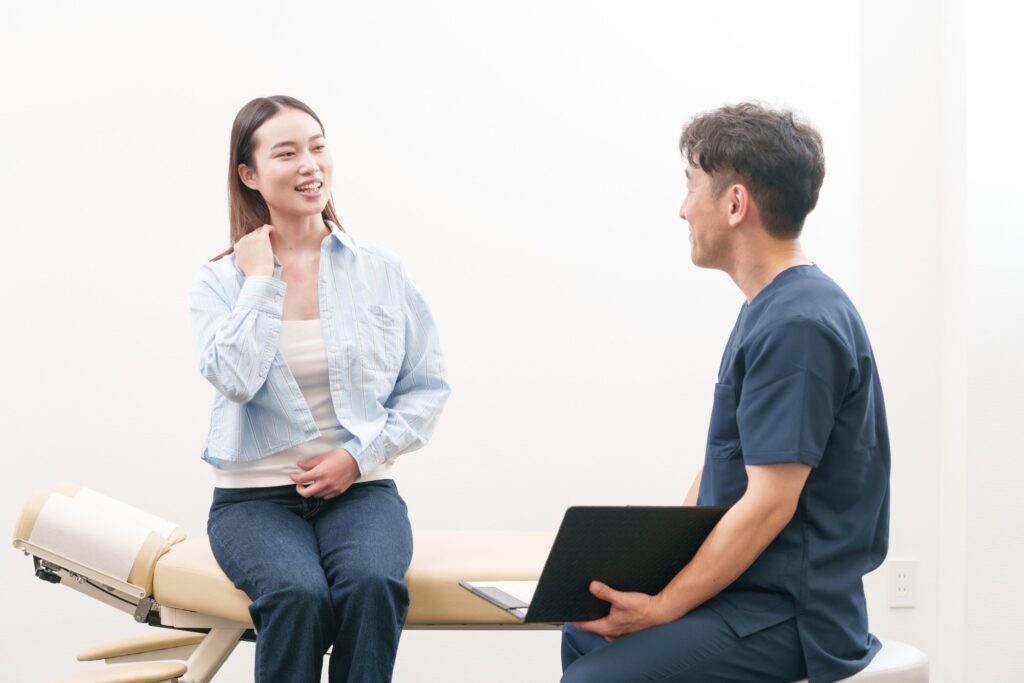 問診で患者さんが笑顔で話し、施術者が耳を傾けている様子