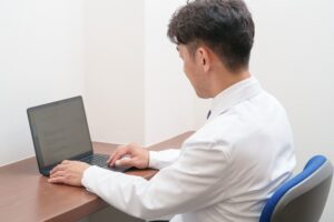 白衣の施術者がノートパソコンで文章を書いている様子