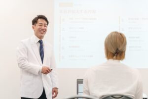 白衣の講師が勉強会でスライドを使って話している様子