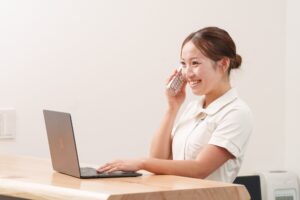 治療院の受付で、スタッフが笑顔で電話に応じている様子